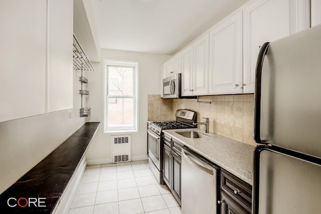 kitchen with white cabinetry, stainless steel appliances, tasteful backsplash, light tile patterned flooring, and sink