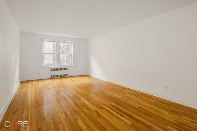 unfurnished room featuring light wood-type flooring and radiator heating unit