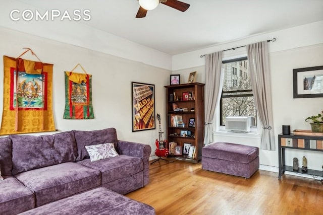 living area with ceiling fan, cooling unit, wood finished floors, and baseboards