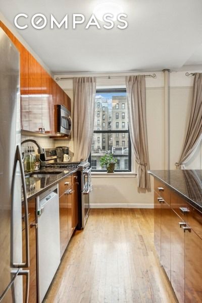 kitchen featuring brown cabinets, light wood-type flooring, baseboards, and stainless steel appliances