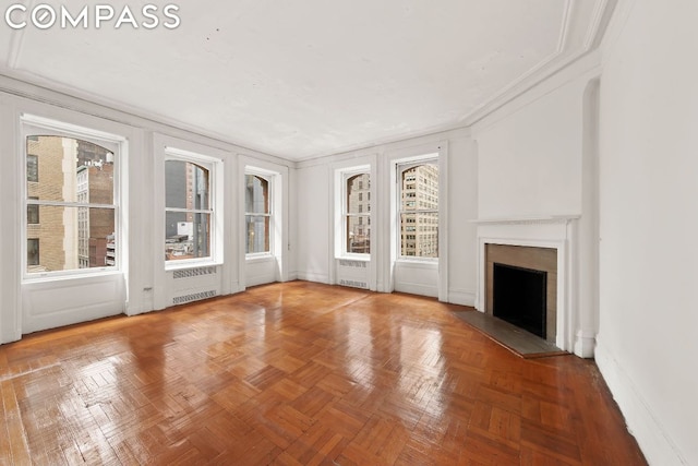 unfurnished living room featuring parquet floors, plenty of natural light, crown molding, and radiator heating unit