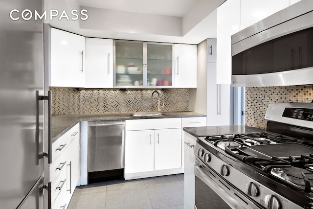 kitchen featuring appliances with stainless steel finishes, a sink, white cabinetry, and tasteful backsplash