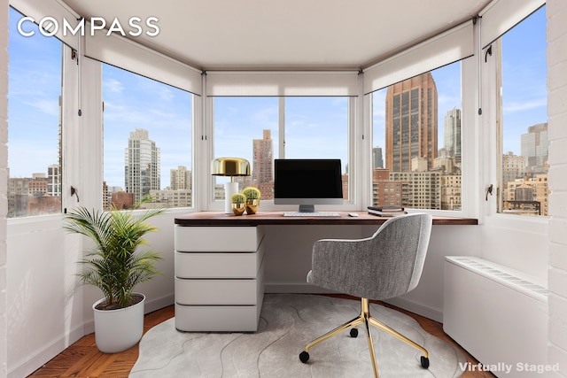 home office with radiator heating unit, baseboards, built in desk, and wood finished floors