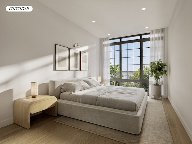 bedroom with a wall of windows and light hardwood / wood-style floors