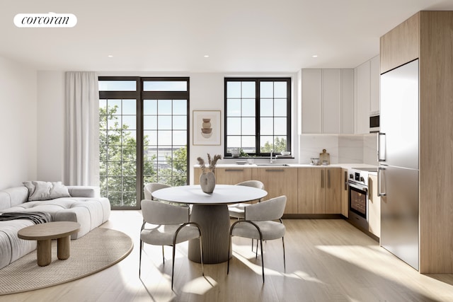 kitchen with tasteful backsplash, range, light hardwood / wood-style floors, and a wealth of natural light