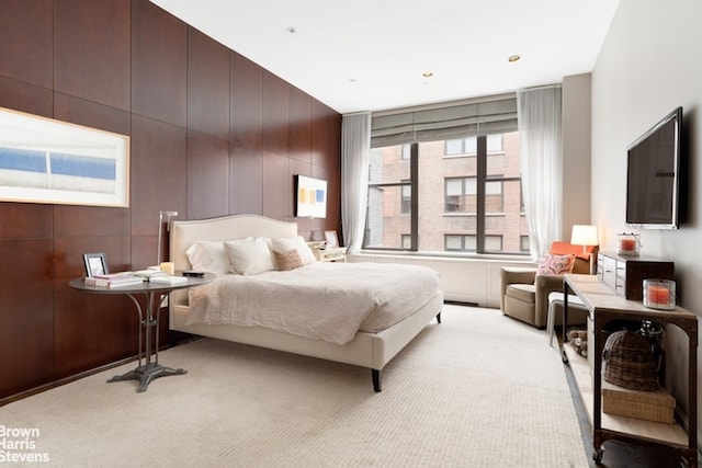 carpeted bedroom featuring wooden walls