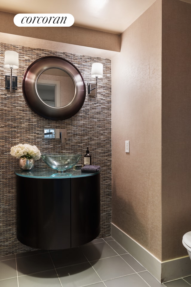 half bath featuring toilet, tile patterned flooring, vanity, and baseboards