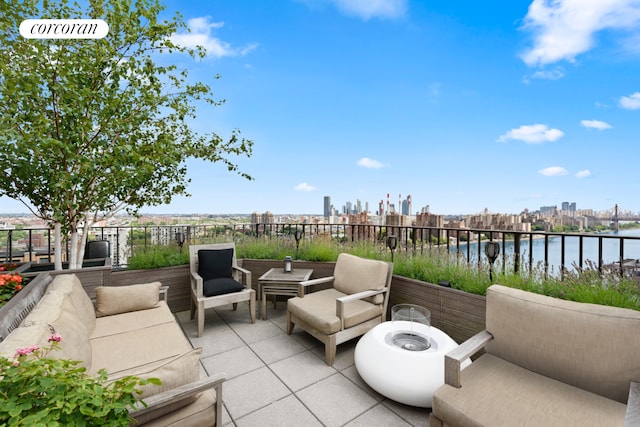 view of patio / terrace featuring a water view, fence, and a city view