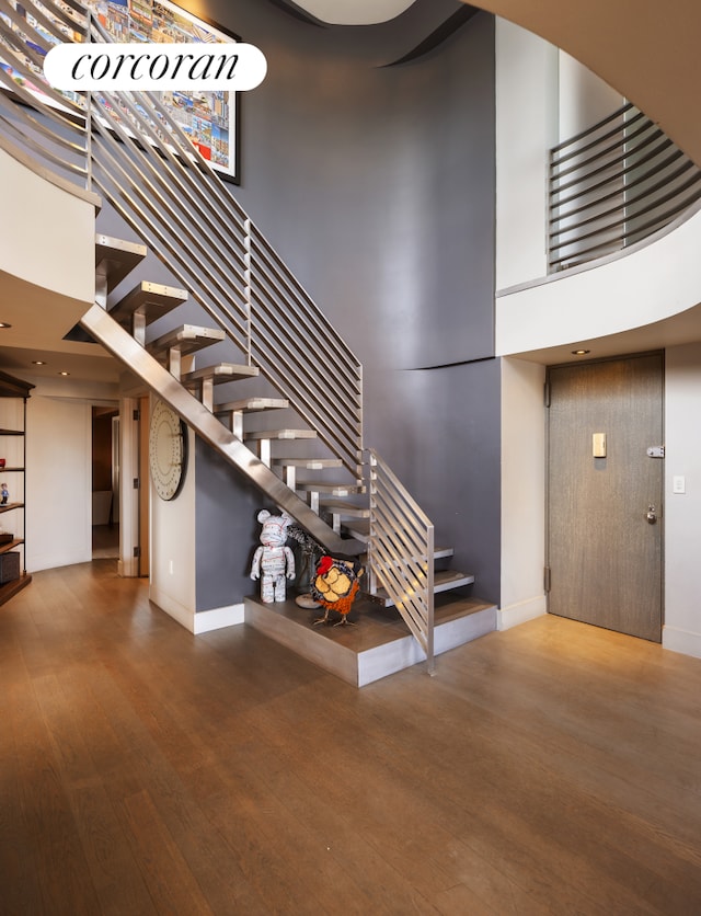 stairs featuring a high ceiling, wood finished floors, and baseboards