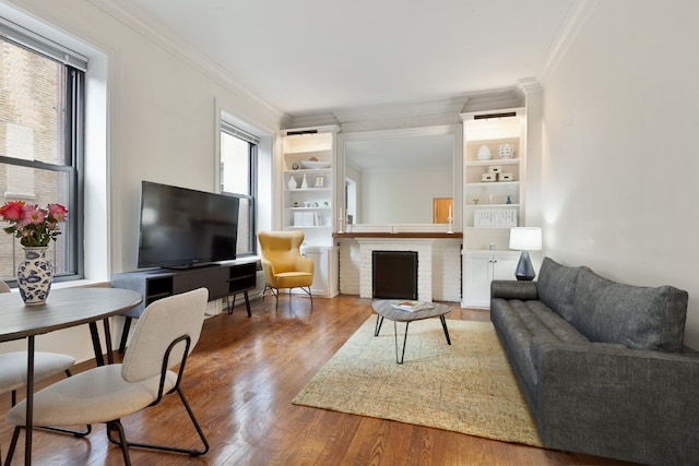 living room with built in features, a fireplace, ornamental molding, and wood-type flooring