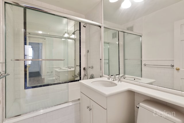 full bathroom with vanity, bath / shower combo with glass door, and toilet