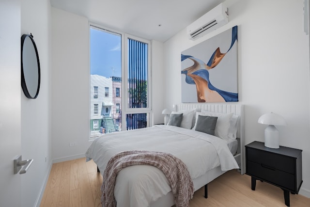 bedroom featuring light hardwood / wood-style floors and a wall mounted AC