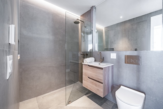 bathroom featuring vanity, toilet, tile walls, and tiled shower