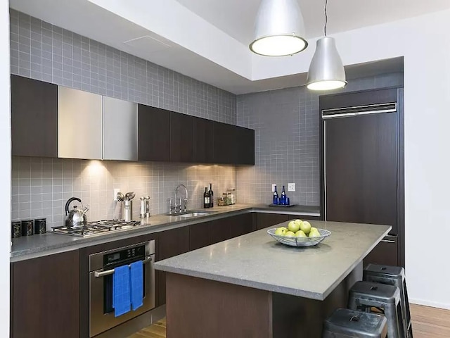 kitchen featuring stainless steel appliances, decorative backsplash, hanging light fixtures, and sink