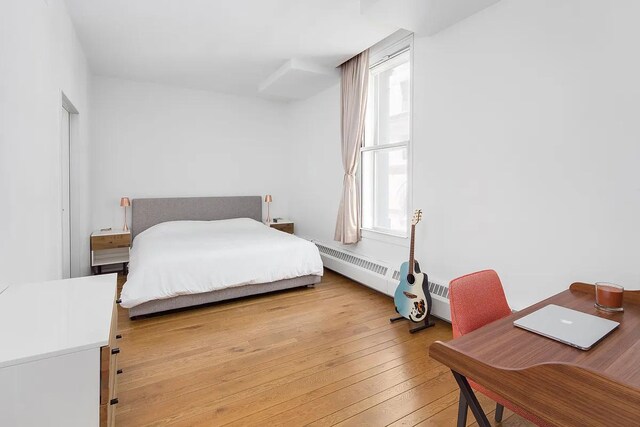 bedroom with light hardwood / wood-style flooring and a baseboard radiator