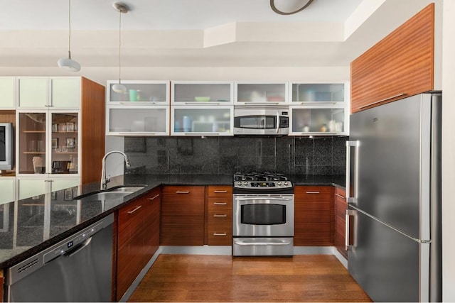 kitchen featuring sink, hanging light fixtures, stainless steel appliances, decorative backsplash, and dark stone counters