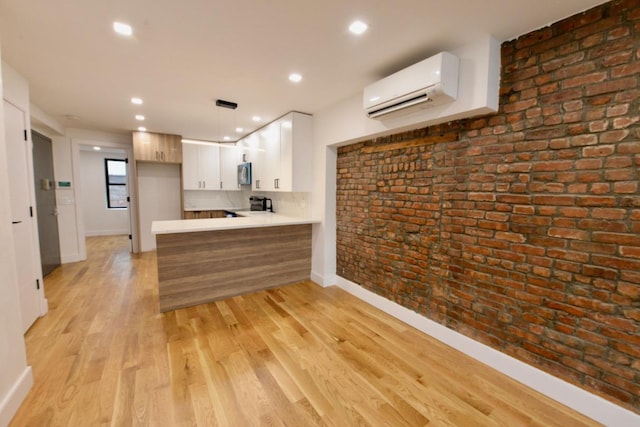 kitchen featuring brick wall, a peninsula, range with electric cooktop, light wood-type flooring, and a wall mounted air conditioner