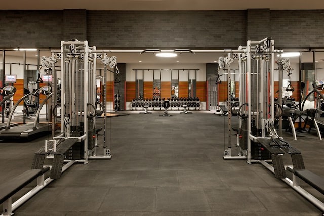 gym featuring a towering ceiling and brick wall