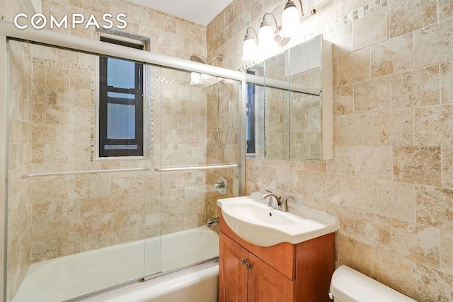 full bathroom featuring combined bath / shower with glass door, vanity, and toilet