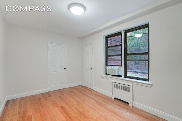 unfurnished room featuring radiator, light hardwood / wood-style floors, and cooling unit