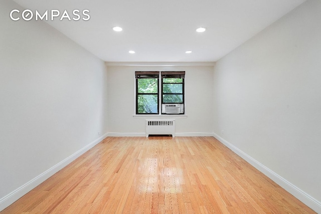 unfurnished room featuring radiator and light hardwood / wood-style floors