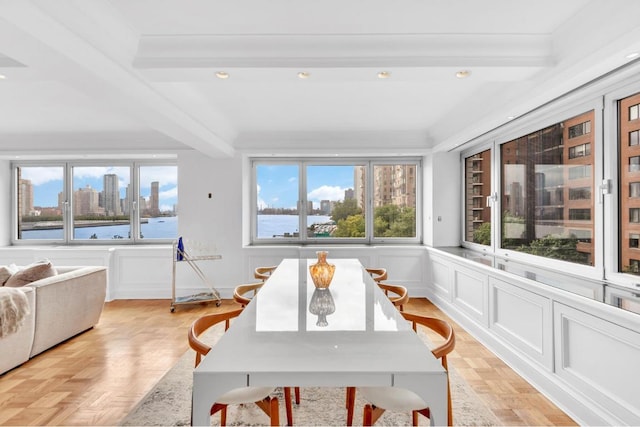 dining space with a water view, ornamental molding, breakfast area, beam ceiling, and light parquet floors