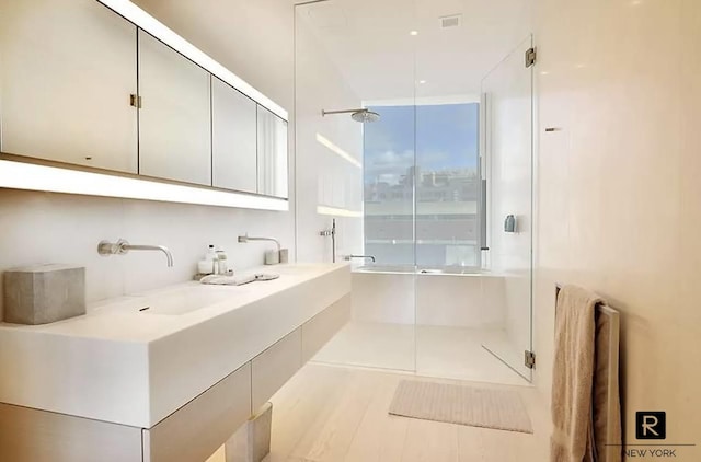 bathroom with double vanity, a shower stall, and visible vents