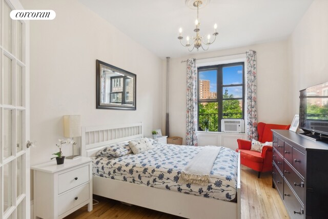 bedroom featuring a chandelier, light wood-style flooring, and cooling unit