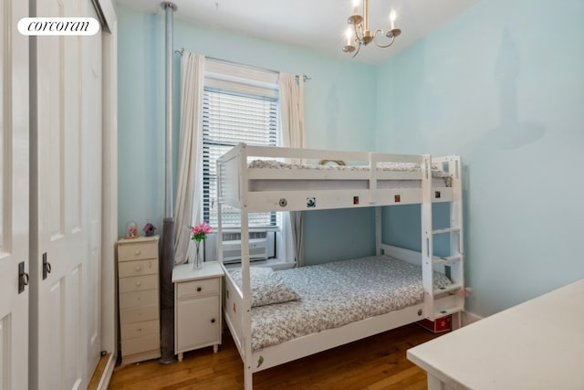 bedroom featuring a chandelier, cooling unit, and wood finished floors