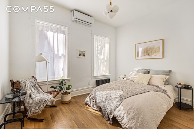 bedroom featuring radiator, baseboards, lofted ceiling, wood-type flooring, and a wall mounted air conditioner