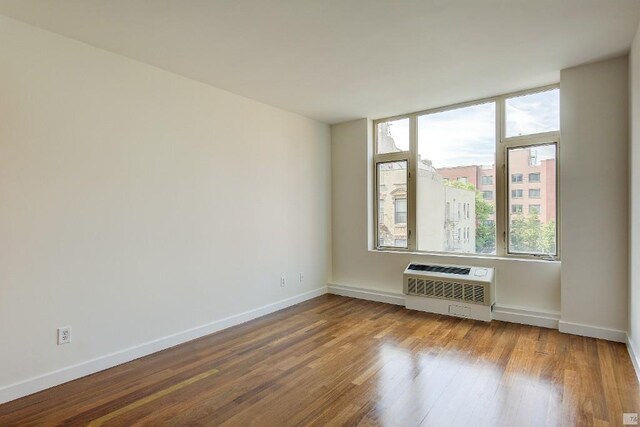 spare room with wood-type flooring and a wall unit AC