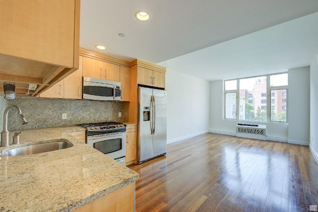 kitchen with sink, appliances with stainless steel finishes, backsplash, light stone countertops, and light brown cabinetry