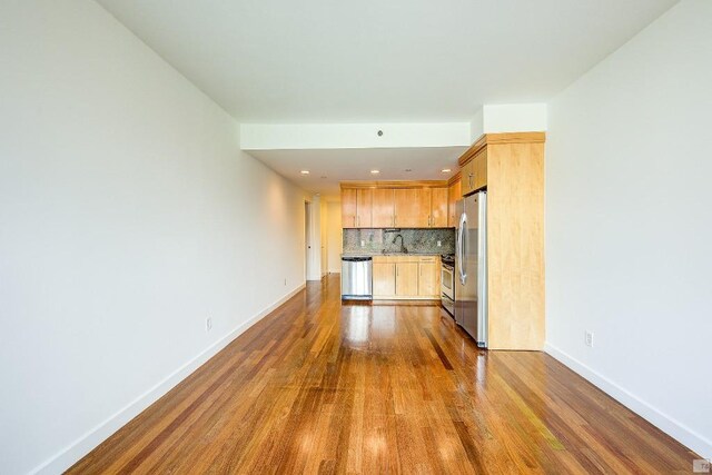 kitchen with hardwood / wood-style floors, tasteful backsplash, sink, stainless steel appliances, and light brown cabinets