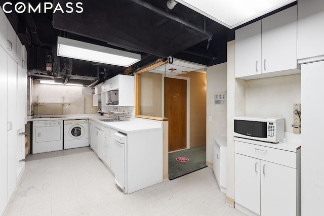 kitchen featuring white cabinets, sink, and washing machine and clothes dryer