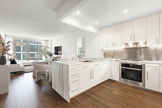 50 Riverside Blvd Unit 15-M, New York City, NY 10069 - kitchen featuring oven, open floor plan, a peninsula, dark wood-type flooring, and decorative backsplash