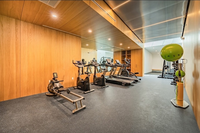 exercise room featuring wood ceiling and wood walls