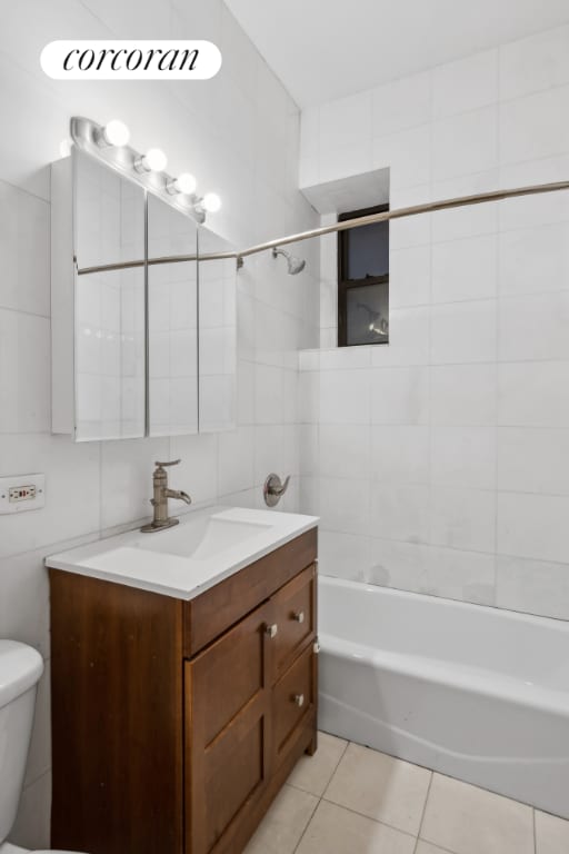 full bathroom with tile patterned floors, toilet, tile walls, vanity, and tiled shower / bath combo