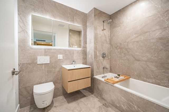 full bathroom with vanity, toilet, tiled shower / bath combo, and tile walls