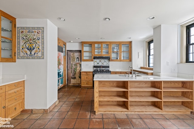 kitchen featuring dark tile patterned floors, kitchen peninsula, sink, and stainless steel gas range