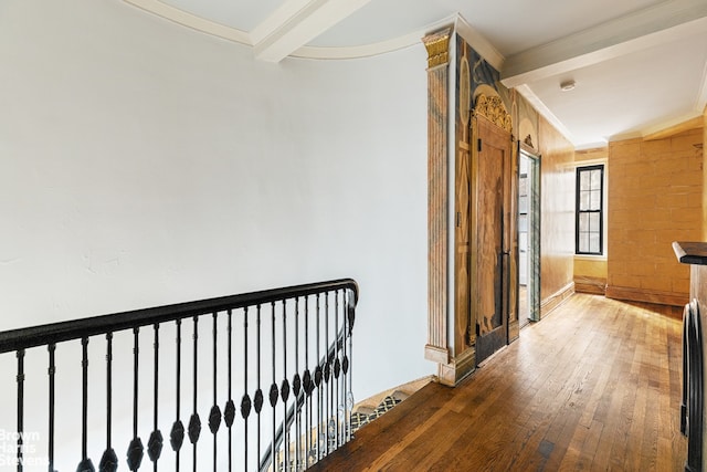 corridor with wood-type flooring, ornamental molding, and beam ceiling