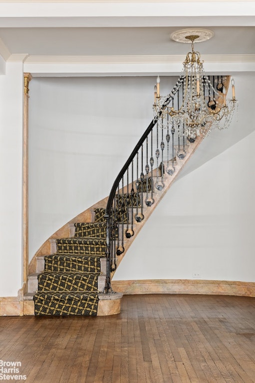 stairs with hardwood / wood-style flooring and a chandelier