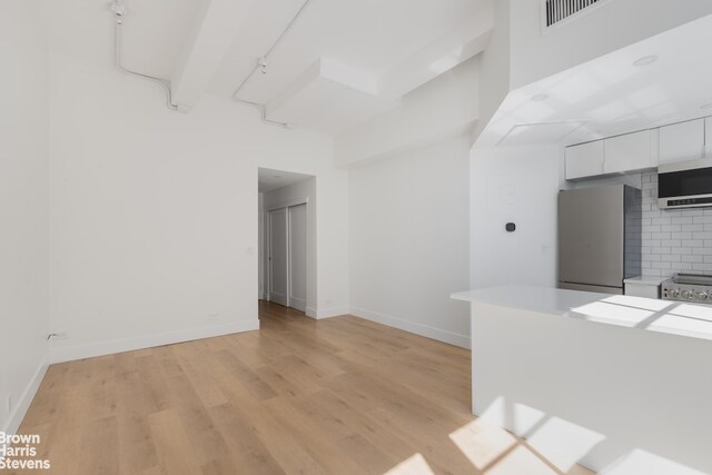 bedroom with hardwood / wood-style flooring, stainless steel fridge, and beam ceiling