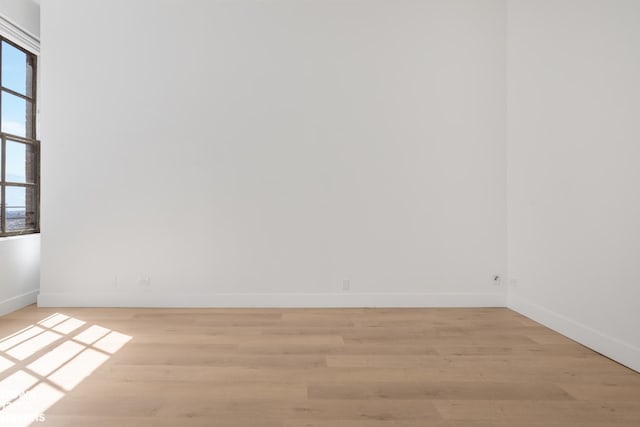 unfurnished room featuring baseboards, a wealth of natural light, and light wood-style floors