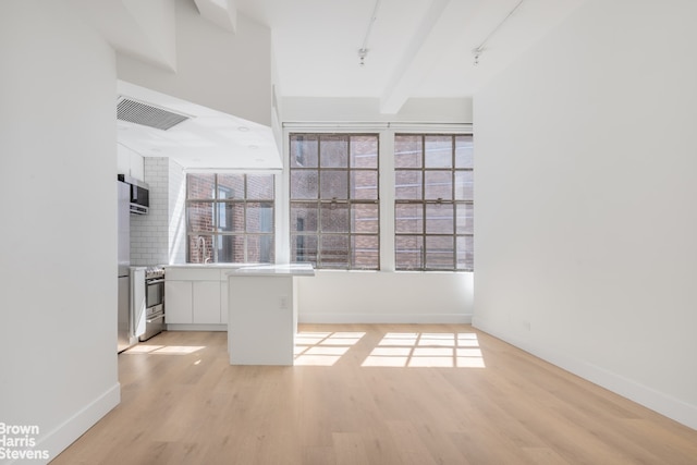 unfurnished room featuring light wood-type flooring, visible vents, beamed ceiling, and track lighting