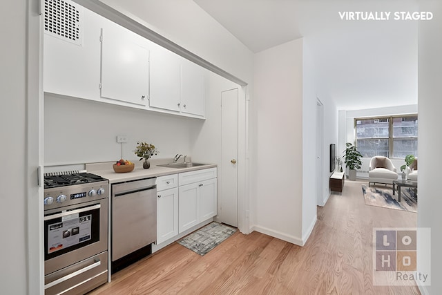 kitchen with light wood finished floors, visible vents, stainless steel appliances, white cabinetry, and a sink