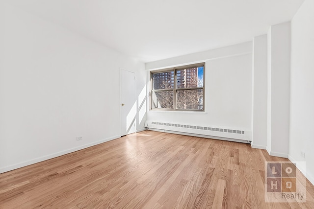 unfurnished room featuring light wood-style floors, baseboards, and a baseboard heating unit