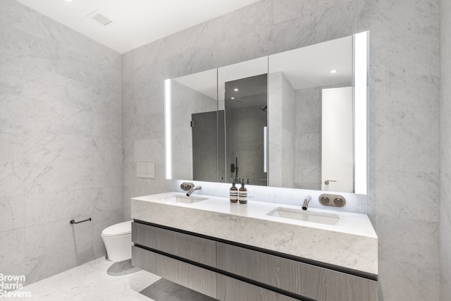 bathroom with vanity, a shower, tile walls, and toilet