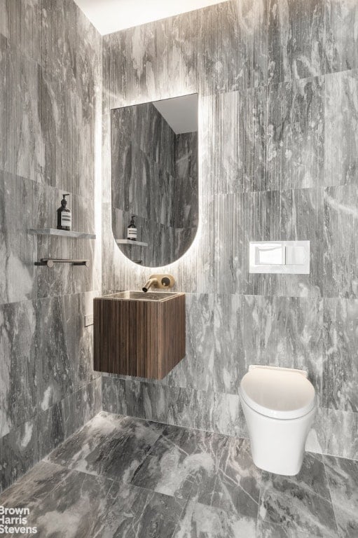 bathroom featuring toilet and tile walls