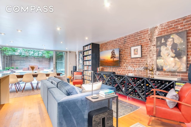 living area with brick wall and wood finished floors