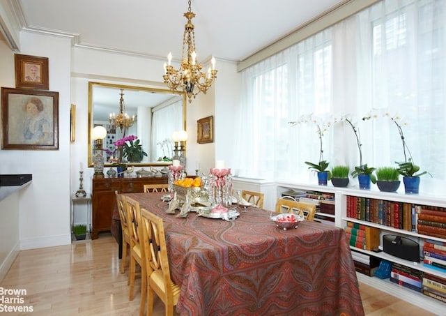 dining space featuring ornamental molding, a chandelier, and light hardwood / wood-style flooring